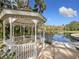 Charming white gazebo overlooking a serene lake surrounded by palm trees and lush vegetation at 136 Bridgeview Ct, Longwood, FL 32779