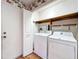 Functional laundry room featuring a washer, dryer, storage shelves and a hardwood floor at 136 Bridgeview Ct, Longwood, FL 32779