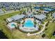 Aerial view of a resort-style community pool, seating, and lush landscaping and tennis courts for recreation at 13828 Tybee Beach Ln, Orlando, FL 32827