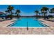 Beautiful swimming pool with lounge chairs, shade umbrellas, and swaying palm trees against a clear sky at 13828 Tybee Beach Ln, Orlando, FL 32827