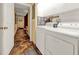 Hallway view of the laundry room features a washer, dryer, and storage cabinets with a doorway to another room at 14143 Conifer Dr, Orlando, FL 32832