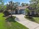 Charming blue home featuring a spacious driveway, well-manicured lawn, and beautiful palm trees at 1570 Westover Loop, Lake Mary, FL 32746