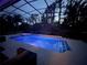 Covered backyard pool and hot tub illuminated with in-pool lighting at 1570 Westover Loop, Lake Mary, FL 32746