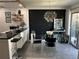 Stylish dining area boasts a clear glass table, modern lighting fixture, and black accent wall next to open kitchen at 1935 Conway Rd # T6, Orlando, FL 32812