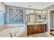 Primary bathroom boasts a soaking tub, wood vanity, decorative wall art, and separate glass shower at 2401 Home Again Rd, Apopka, FL 32712