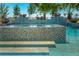 Close-up of mosaic tile pool with steps, integrated spa, and water feature at 2458 Dream Home Ct, St Cloud, FL 34772