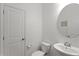 Small bathroom with a white toilet, a round mirror over a white sink, and white walls at 2628 Cedar Shake Ct, Oviedo, FL 32765