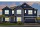 Charming two-story home featuring a stone facade, gray paint, and a two-car garage at dusk at 2628 Cedar Shake Ct, Oviedo, FL 32765