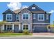 Elegant two-story home featuring a stone facade, blue siding, manicured landscaping, and a spacious two-car garage at 2628 Cedar Shake Ct, Oviedo, FL 32765