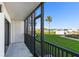 A screened balcony with a view of lush landscaping, a waterway, and a clear blue sky with a palm tree at 2700 N Peninsula Ave # 215, New Smyrna Beach, FL 32169