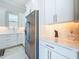 This bright kitchen features white cabinetry, stainless steel appliances, tile backsplash, and modern countertops at 3182 Sailing Pier Ave, Winter Garden, FL 34787