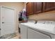 A functional laundry room with a utility sink, washer, dryer, and overhead cabinets for efficient storage at 3375 Bellino Blvd., New Smyrna Beach, FL 32168