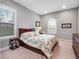 Bedroom features multiple windows, a wooden bed frame with floral comforter, side table with lamp and carpeted floors at 3664 Farm Bell Pl, Lake Mary, FL 32746