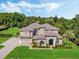 Beautiful two-story home featuring a tile roof, arched entryway, manicured lawn and mature landscaping at 3664 Farm Bell Pl, Lake Mary, FL 32746