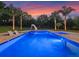 Inviting pool with lounge chairs and slide, with a colorful sunset in the background at 3664 Farm Bell Pl, Lake Mary, FL 32746