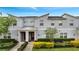 Charming townhome featuring a modern facade, red door, covered entry, and professionally landscaped front yard at 368 Ocean Course Ave, Davenport, FL 33896