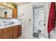 Bathroom with a wooden vanity, neutral patterned wallpaper, and a walk-in shower at 5547 Kingswood Dr, Orlando, FL 32810
