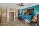 Bright bedroom features modern decor, a king bed, tile floors, a ceiling fan, and a barn door to the ensuite bathroom at 789 Errol Pkwy, Apopka, FL 32712