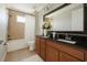 Bathroom features dual sinks with dark granite counters, wood cabinets, a shower-tub combo, and tile floors at 9895 Winnington St, Orlando, FL 32832