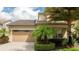 Charming two-story home with a well-manicured lawn, palm trees, and a two-car garage at 9895 Winnington St, Orlando, FL 32832