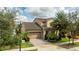 Charming two-story home with a well-manicured lawn, mature trees, and a driveway leading to an attached garage at 9895 Winnington St, Orlando, FL 32832