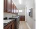 Well-equipped laundry room features dark wood cabinets, washer and dryer, granite countertop, and a built-in sink at 9895 Winnington St, Orlando, FL 32832