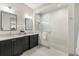 Bright bathroom featuring double sinks, black cabinets, a white countertop, and a glass-enclosed shower at 1114 Georgia Blvd, Orlando, FL 32803