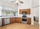 Bright kitchen featuring wood cabinets, stainless steel appliances, and a large window overlooking the backyard at 118 White Birch Dr, Kissimmee, FL 34743
