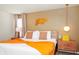 This bedroom has warm tones, with an orange throw blanket and unique wall decor, providing a cozy space at 1293 Emerald Row, Clermont, FL 34714