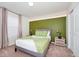 This bedroom features a green accent wall, carpeted floors, and a modern stylish decor at 1293 Emerald Row, Clermont, FL 34714