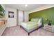This bedroom features a green accent wall, carpeted floors, and a modern stylish decor at 1293 Emerald Row, Clermont, FL 34714