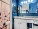 This bathroom features blue accent walls, a shower with a floral shower curtain, and vanity with tiled countertop at 1296 Gage Ave, Deltona, FL 32738