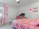 This bedroom has a ceiling fan, a pink bedspread, and closet with louvered doors at 1296 Gage Ave, Deltona, FL 32738