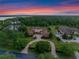 Stunning aerial view of an estate home, lush landscaping, and a serene lake at sunset at 1526 Bluewater Run, Chuluota, FL 32766