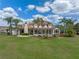 Expansive backyard features a pristine pool, lush lawn, mature palms, and a covered patio area at 1526 Bluewater Run, Chuluota, FL 32766