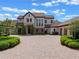Elegant home exterior with brick driveway, manicured bushes, stone accents, and three-car garage at 1526 Bluewater Run, Chuluota, FL 32766