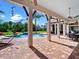 Luxurious pool area with brick patio, hammock, outdoor dining, fireplace, and lush landscaping at 1526 Bluewater Run, Chuluota, FL 32766