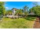Expansive backyard featuring a pool with a rock waterfall, a covered patio, lush lawn and beautiful tropical landscaping at 1665 Temple Dr, Winter Park, FL 32789