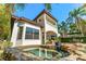 A luxurious backyard with a stone-trimmed pool and spa, complemented by a covered outdoor living area and lush landscaping at 1665 Temple Dr, Winter Park, FL 32789