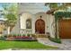 Stunning front exterior featuring colorful flowerbeds and an elegant doorway with a beautiful wood door at 1665 Temple Dr, Winter Park, FL 32789