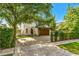 Beautiful two-story home features lush landscaping, paver driveway, wood garage door covered by greenery, and balcony at 1665 Temple Dr, Winter Park, FL 32789