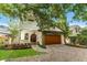 Charming two-story home features a lush landscaped yard, wood garage door covered by greenery, and second story balcony at 1665 Temple Dr, Winter Park, FL 32789