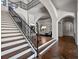 Bright foyer boasts a staircase with dark iron railings and herringbone-patterned wood floors at 16812 Vinci Way, Bella Collina, FL 34756