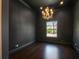 Minimalist style empty room with dark walls, chandelier, wood floors, and natural light from large window at 16812 Vinci Way, Bella Collina, FL 34756