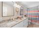 Bright bathroom featuring double sinks, granite countertop, and shower with multi-colored curtain at 2132 Rouse Lake Rd, Orlando, FL 32817