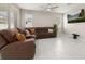 Spacious living room features tile flooring, a ceiling fan, large windows and a large sofa at 236 Pink Ibis Bnd, St Cloud, FL 34772