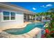 A luxurious pool and spa surrounded by a lush garden and a covered patio with outdoor seating at 2454 Dream Home Ct, St Cloud, FL 34772