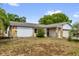 Single story home with stone accent, overgrown lawn, and an attached garage at 3218 Cimarron Dr, Orlando, FL 32829