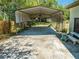 A metal carport structure attached to a home with plants, hose, and other items at 3975 Rambler Ave, St Cloud, FL 34772