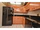 A compact kitchen featuring black appliances and wood cabinetry at 400 E Colonial Dr # 1003, Orlando, FL 32803